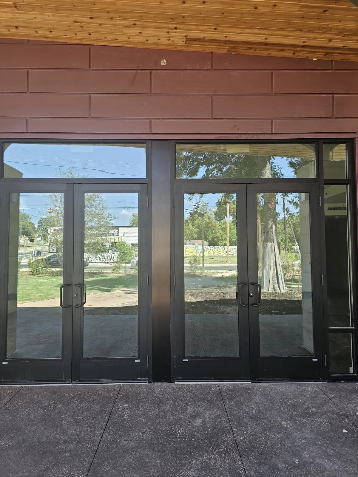 Glass entrance doors of the WOW Heritage Center looking out onto the East Austin neighborhood across the street.