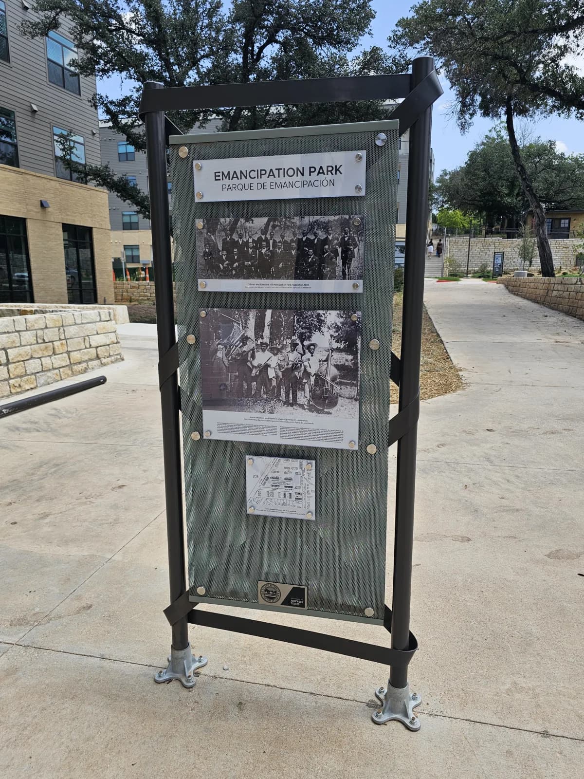 An Emancipation Park interpretive kiosk at Rosewood Courts, with archival photographs of the Emancipation Park Association and an early Juneteenth celebration.